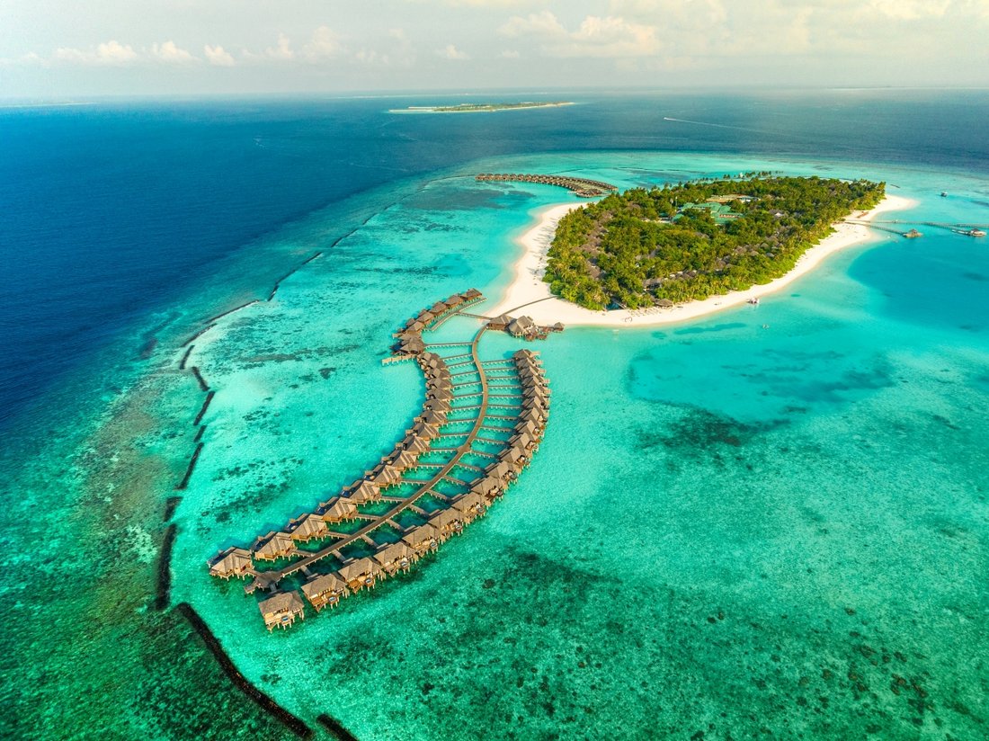Overwater villas curving into a turquoise Maldives lagoon